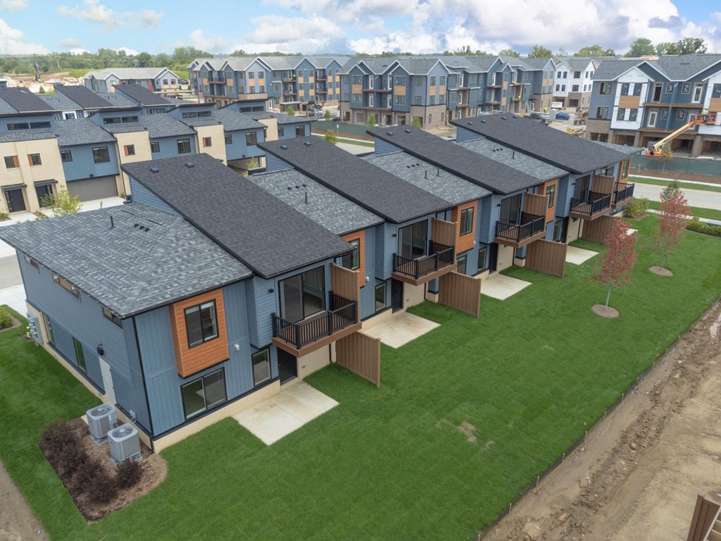 an aerial view of a row of blue houses with gray roofs and green grass