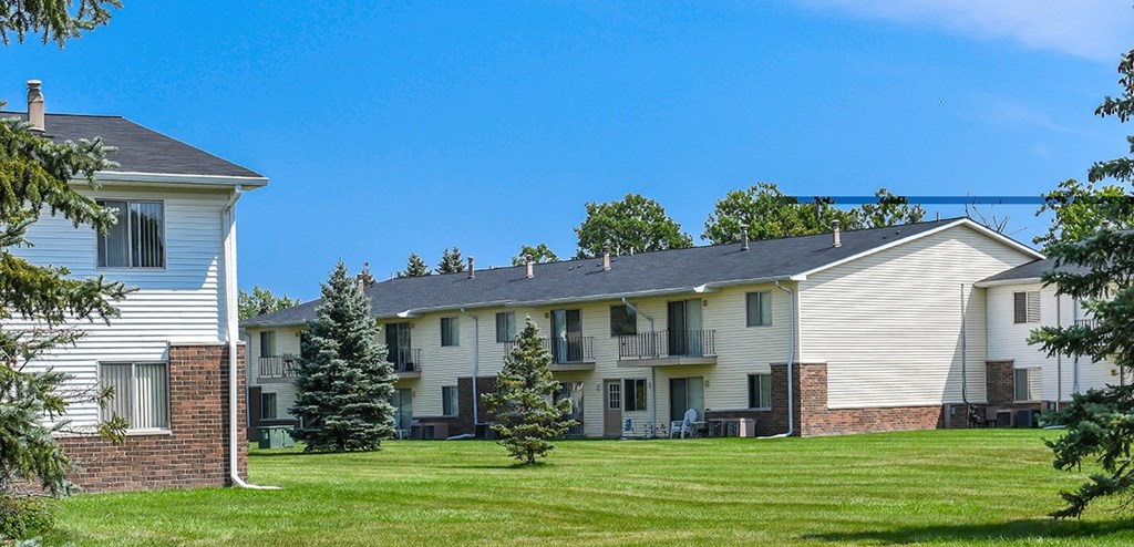 Apartment complex with a white house on the left and a two-story building on the right.