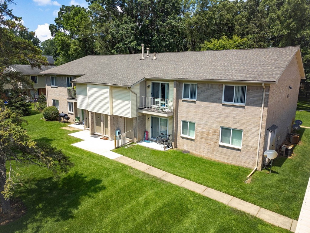 an aerial view of an apartment building with a lawn and trees