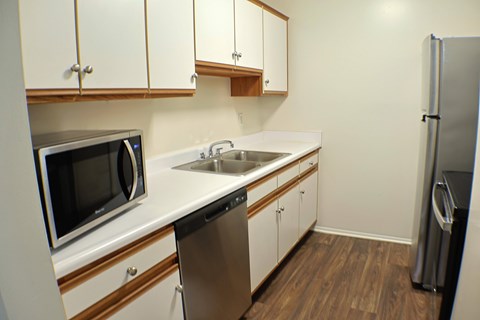 A kitchen with white cabinets and a black fridge.