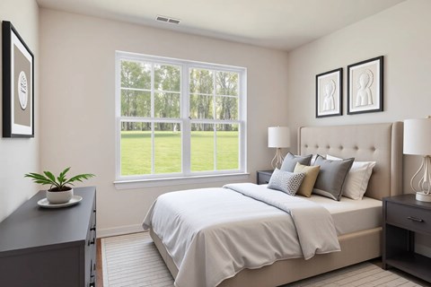 A bedroom with a large bed and a window overlooking a green lawn.