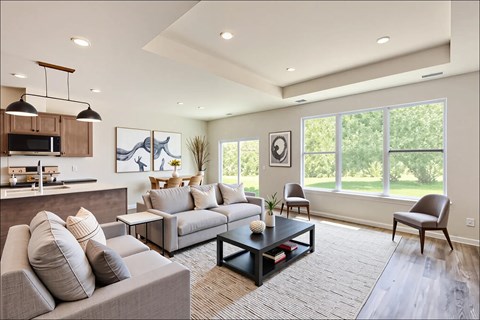 A modern living room with a grey sofa, a coffee table, and a kitchen area in the background.