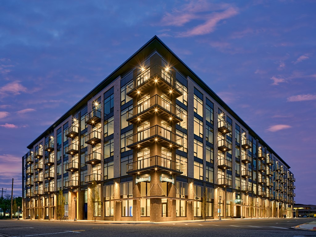 A modern building with a lot of windows and lights on.