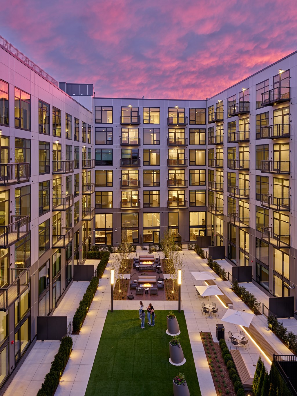 A modern building with a courtyard and people sitting on a bench.
