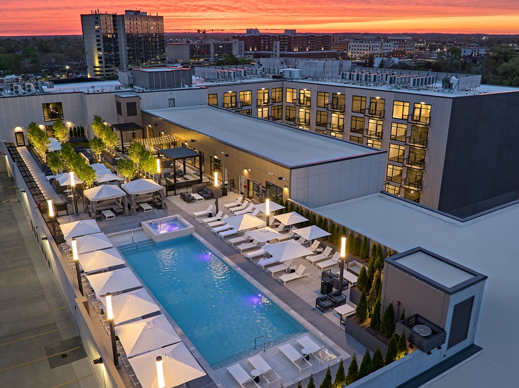 A rooftop pool area with lounge chairs and umbrellas.