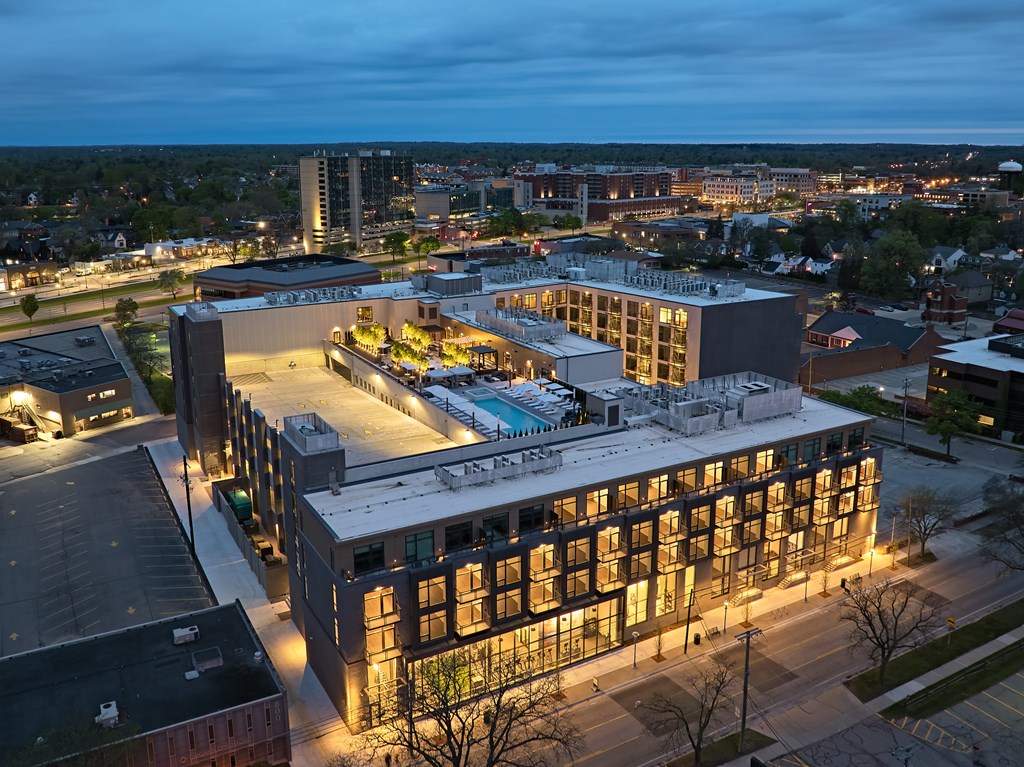 A modern building with a pool in the middle of it is lit up at night.