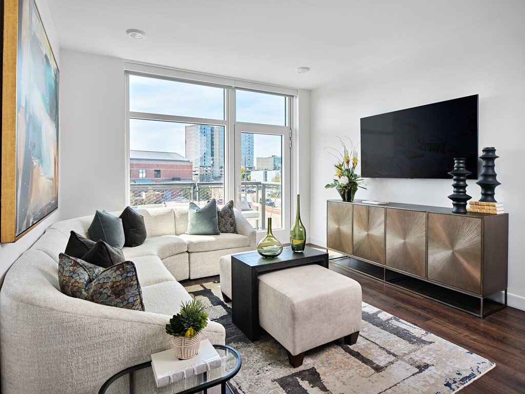 A living room with a white couch, a coffee table, and a large window.