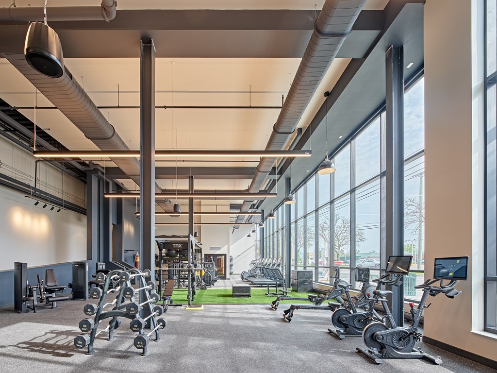 A gym with a variety of equipment including treadmills, weights, and exercise bikes.
