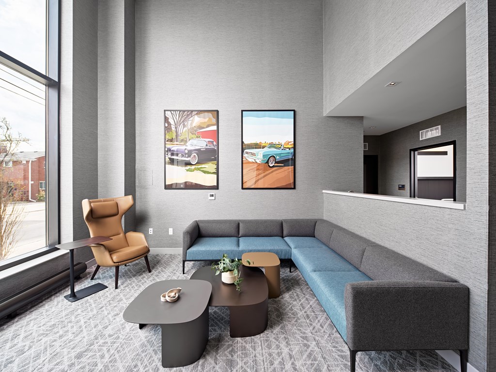 A modern living room with a grey sofa, a brown armchair, a coffee table, and two framed pictures on the wall.