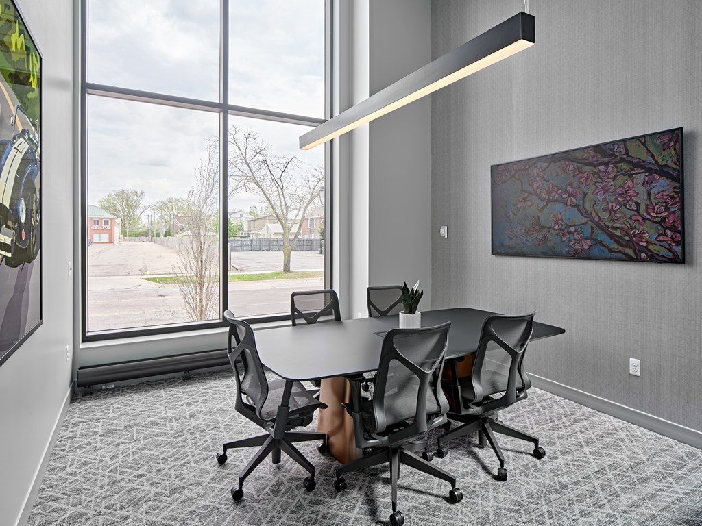 A conference room with a table, chairs, and a painting on the wall.