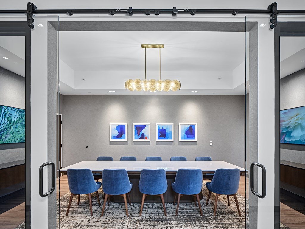 A conference room with a long table and blue chairs.