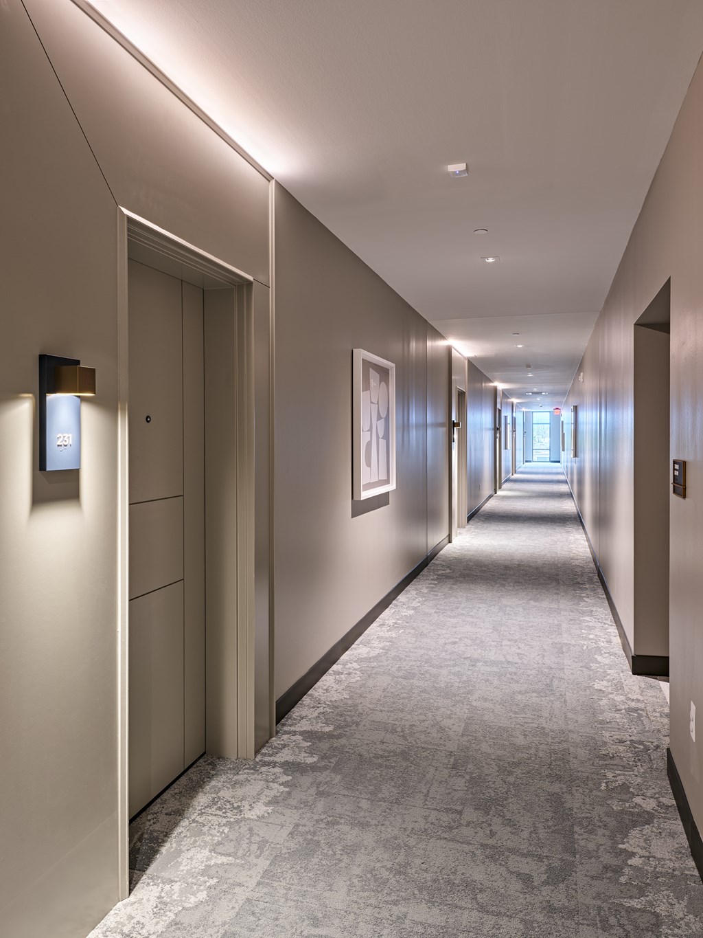 A long hallway with doors on the left and a light on the wall.