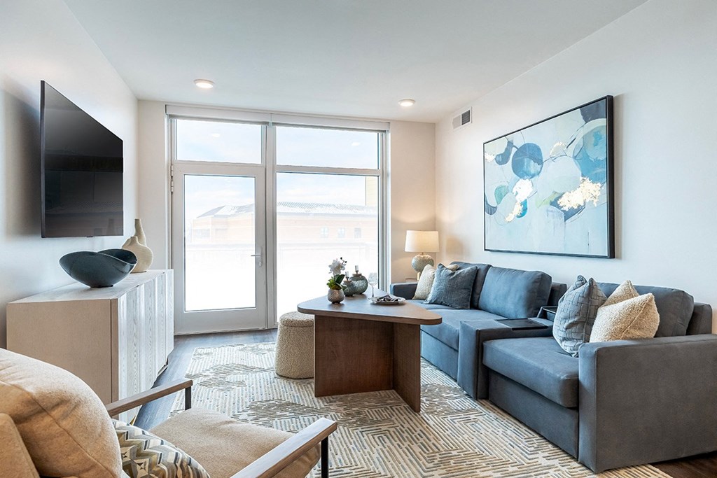 A living room with a grey couch, a coffee table, and a painting on the wall.