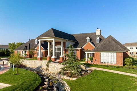 a large brick house with a front porch and a landscaped yard
