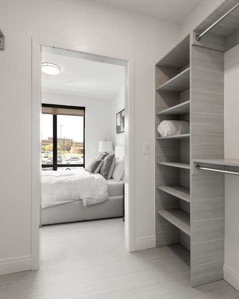 A white bedroom with a large bed and a built in shelf.