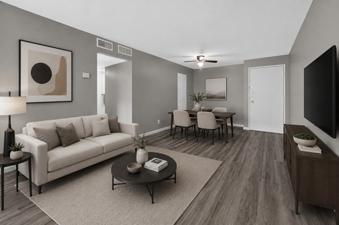 A living room with a white couch, a coffee table, and a television.