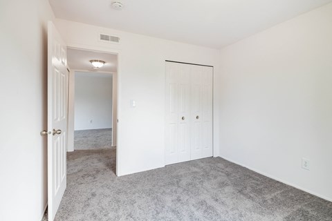 A white door is open to a room with a carpeted floor.