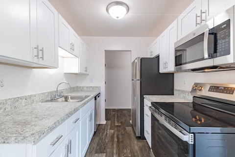 A kitchen with white cabinets and a black refrigerator.