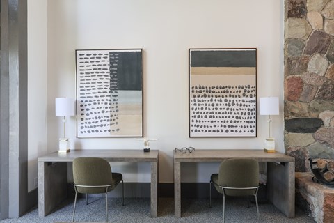 Two desks with chairs and lamps in front of a stone wall.