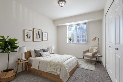 A bedroom with a bed, chair, and a plant.