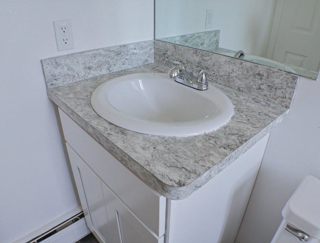 A white sink is on a marble countertop.