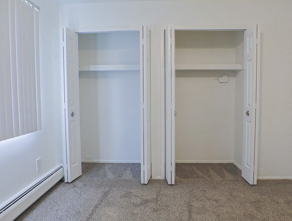 A white room with two open doors and a carpeted floor.