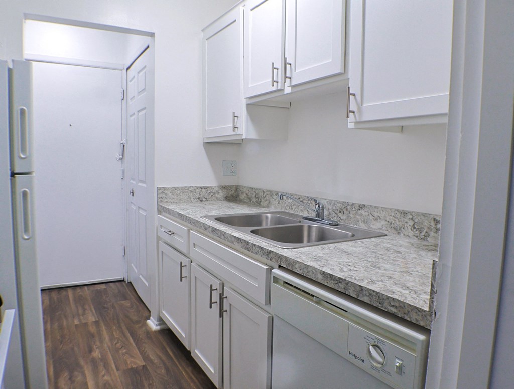 A kitchen with white cabinets and a marble countertop.