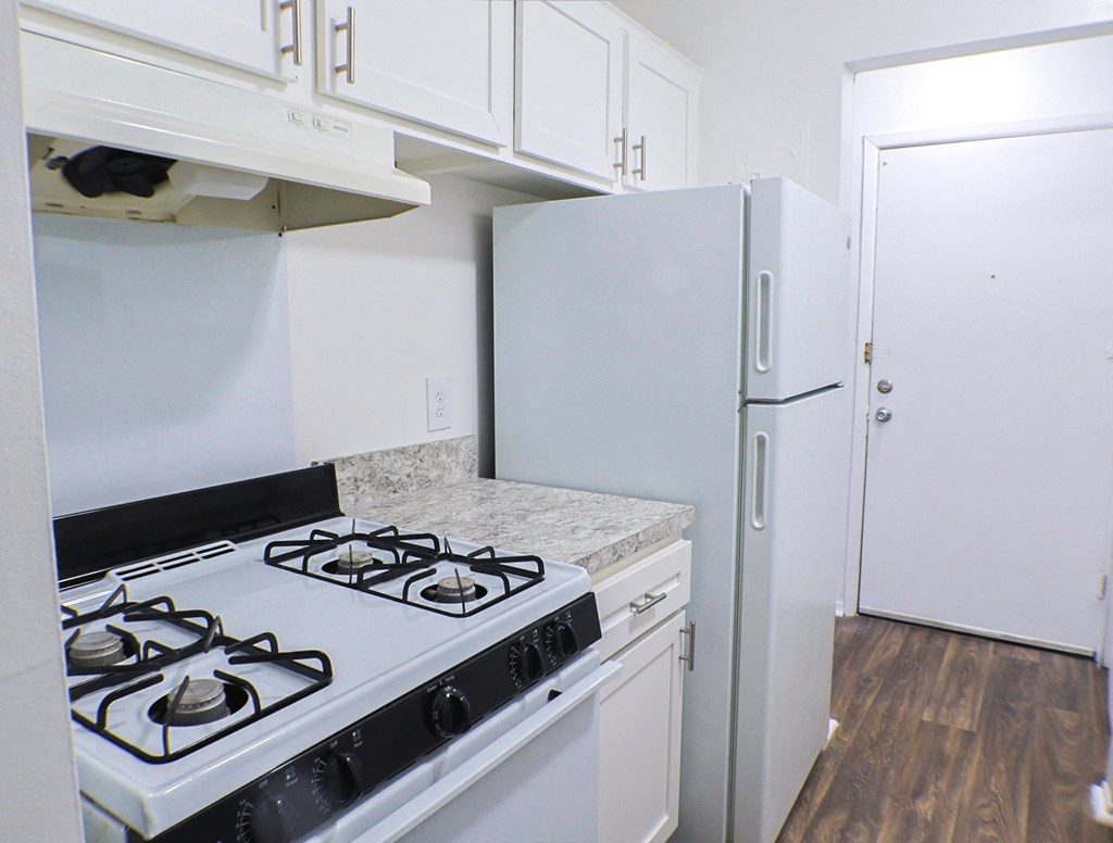 A white kitchen with a black stove top oven.