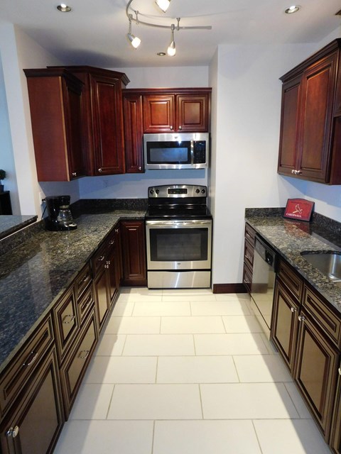 A kitchen with dark wood cabinets and granite countertops.