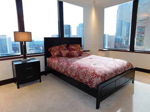 A bedroom with a large bed and a city view.