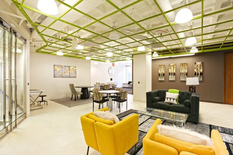 A living room with a yellow chair and a glass coffee table.