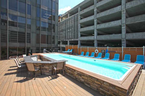 A pool with a table and chairs is surrounded by a wooden deck.