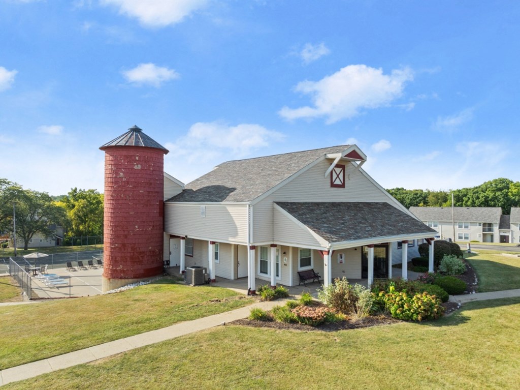 A red brick tower stands next to a white building with a gabled roof.