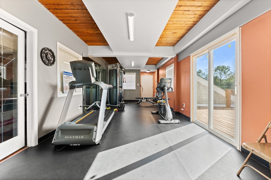 A gym with a treadmill, elliptical trainer and a stationary bike.