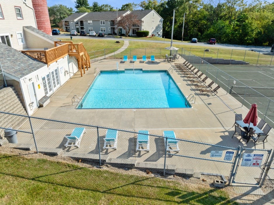 A large outdoor swimming pool surrounded by a fence and lounge chairs.