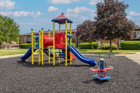 A playground with a blue and yellow slide and a red and yellow structure.