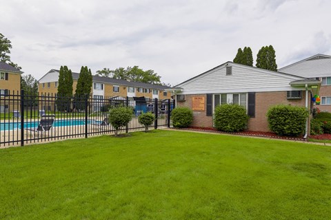 A grassy area in front of a building with a pool.