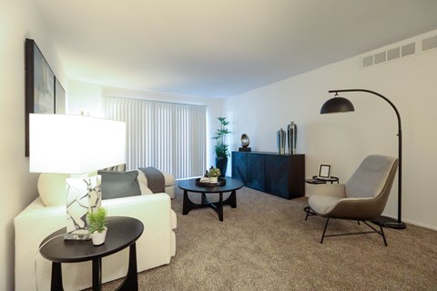 A living room with a white couch, a black table, and a chair.