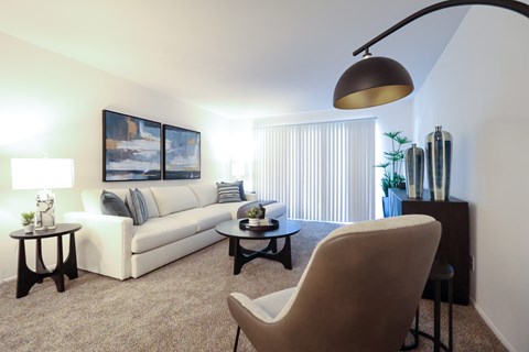 A living room with a white couch, a brown chair, and a painting on the wall.