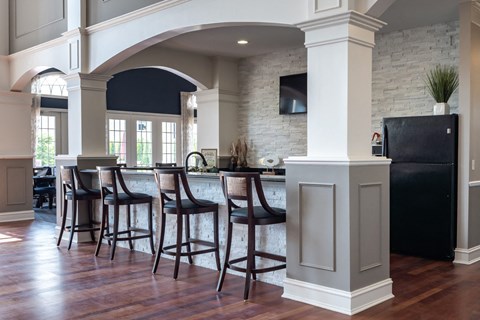 A kitchen with a black fridge and wooden floors.