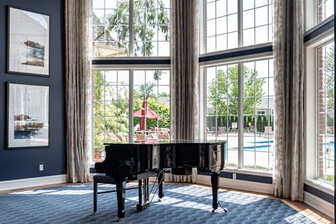 a living room with a piano and a large window
