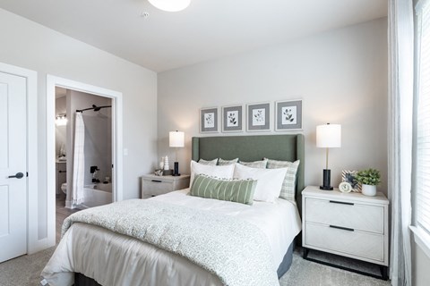 a bedroom with a bed and two nightstands and a wall with a painting