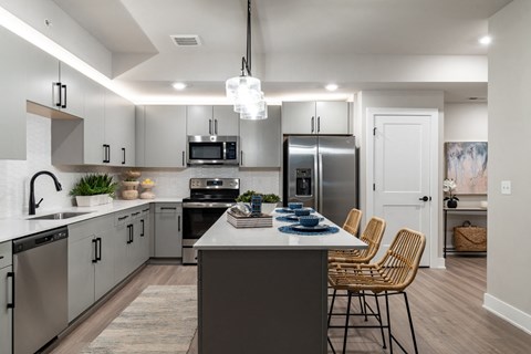 an open kitchen with stainless steel appliances and a large island with chairs