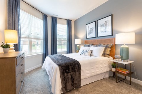 A bedroom with a large bed and a nightstand with a lamp.