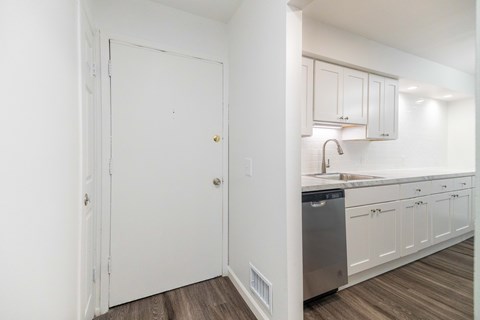 A kitchen with white cabinets and a wooden floor.