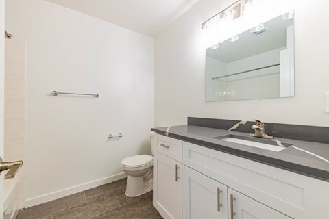 A white bathroom with a toilet, sink, and mirror.