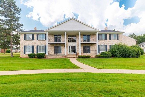 A large house with a front porch and a lawn in front.