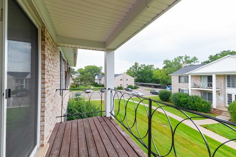 A balcony with a black railing and a brown wooden floor.