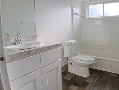 A white bathroom with a marble sink and toilet.