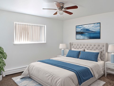 A bedroom with a bed, a ceiling fan, and a painting of a mountain.